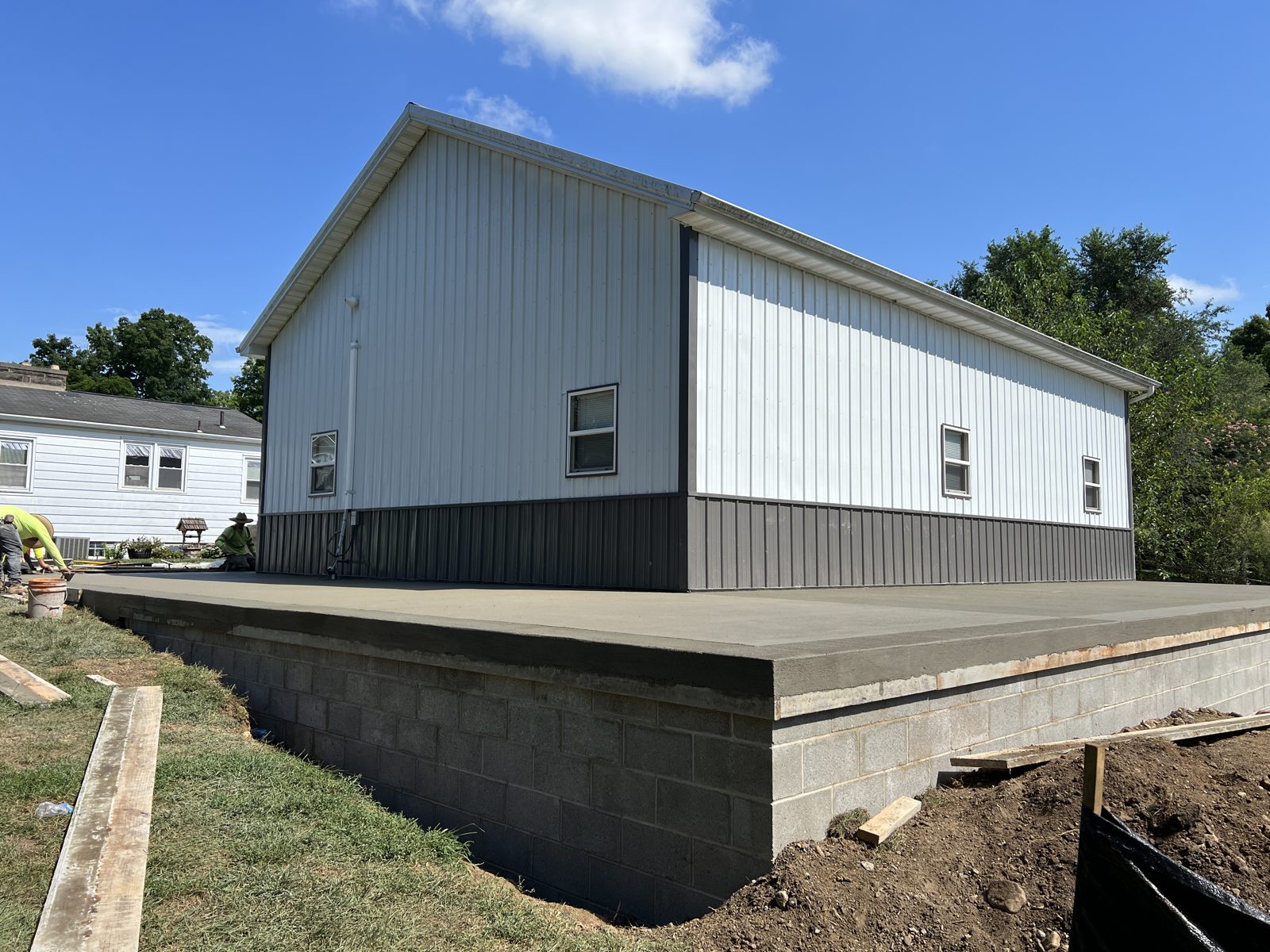 Poured concrete foundation wall and slab supporting a new pole barn build