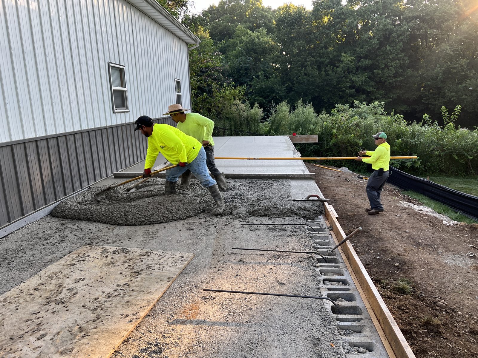 Grade Point Solutions crew placing and finishing a concrete slab along a new foundation wall