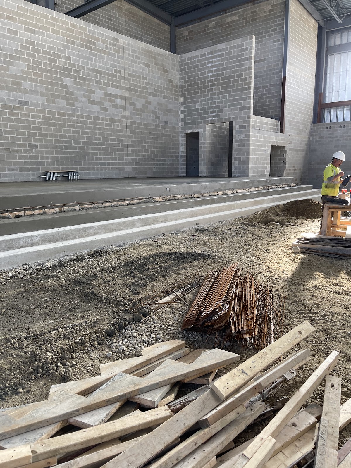 Commercial new-construction slab pour with rebar cages staged along a CMU building interior