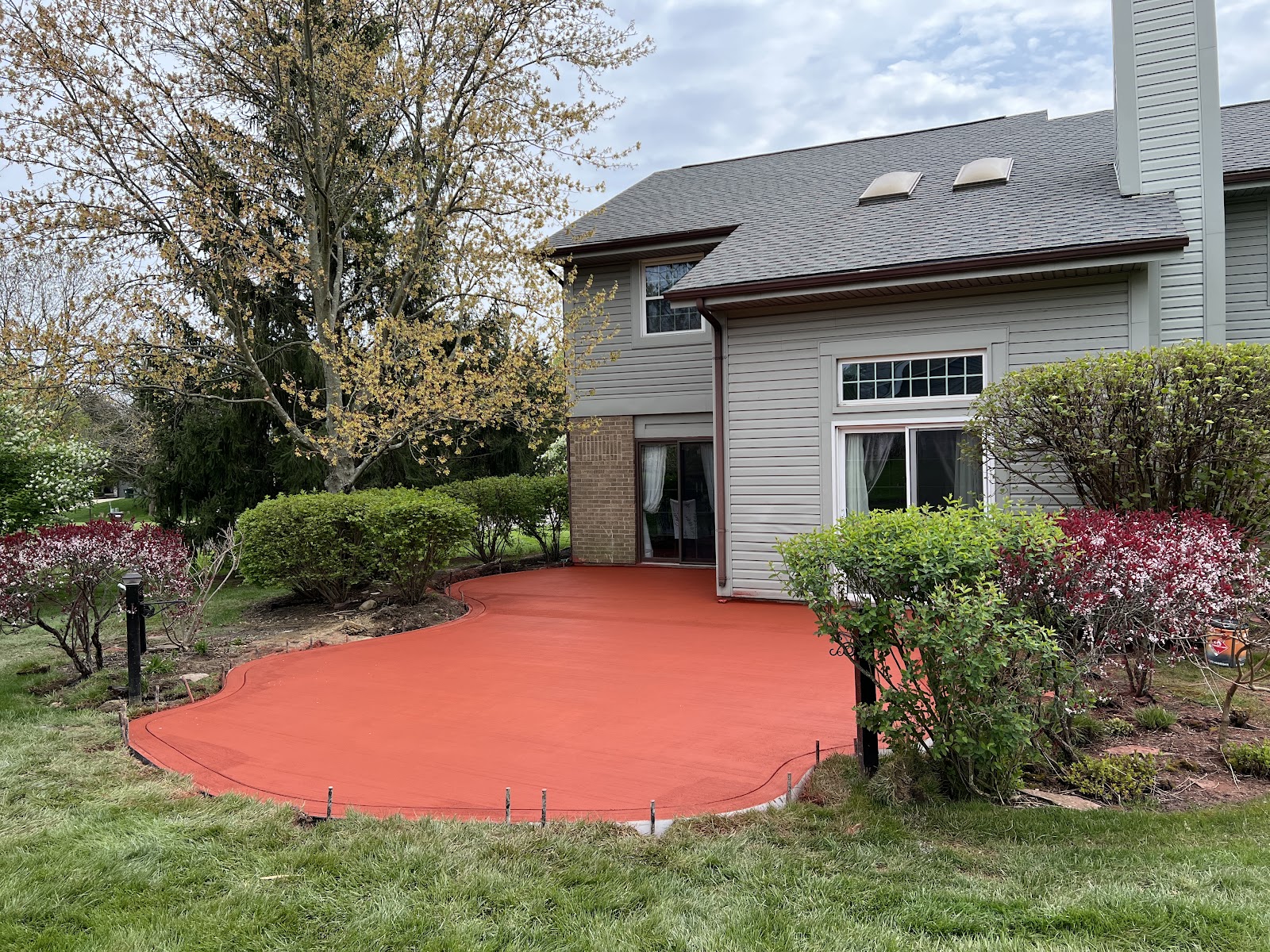 Bold terracotta-stained curved concrete patio off the back of a two-story home
