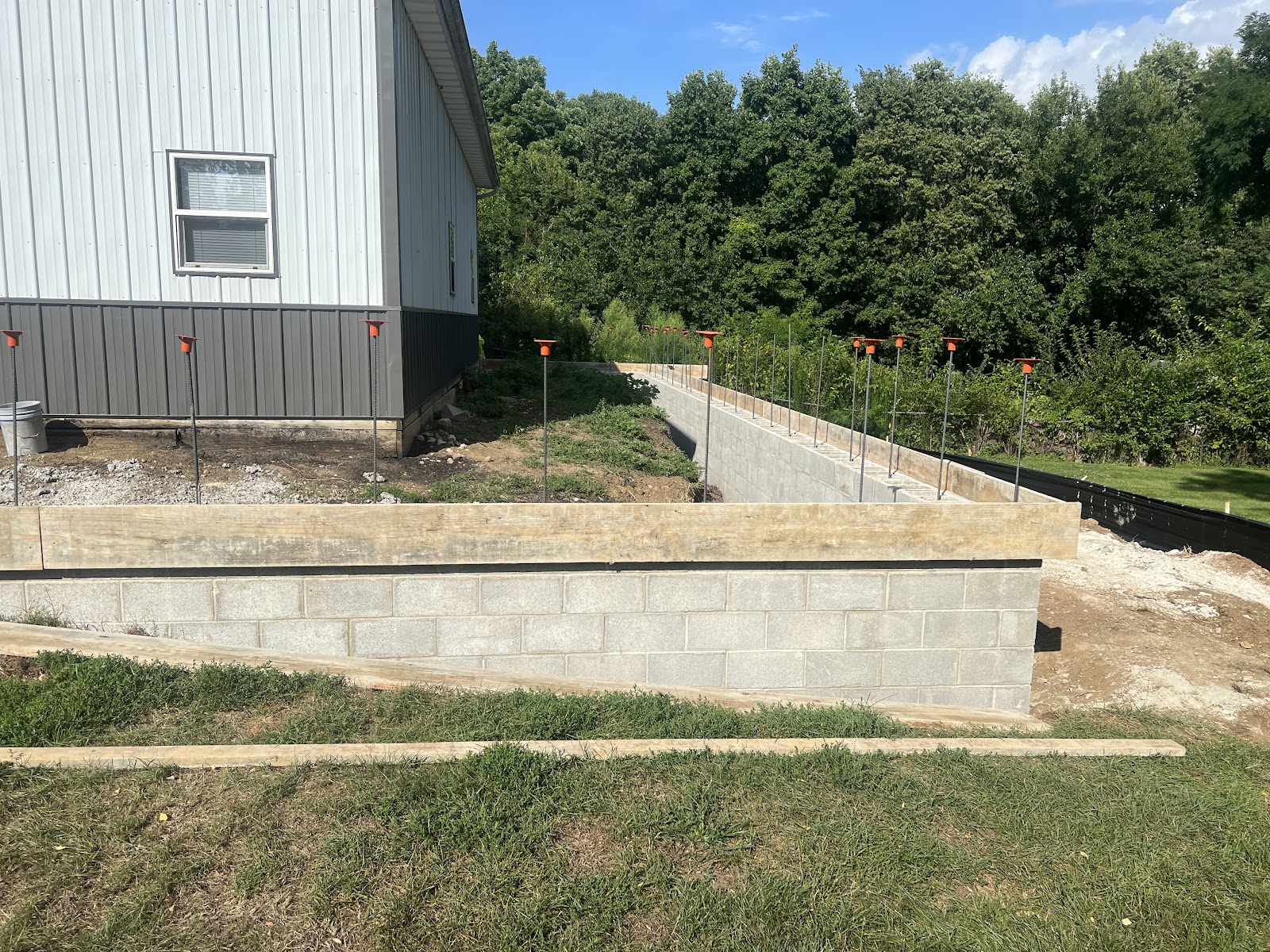 Engineered CMU block retaining wall with rebar dowels along a pole barn build